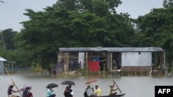 People ride on a boat through flooded waters in Sunamgong, Bangladesh, July 14, 2020.