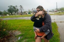 Danielle Fontenot runs to a relative's home in the rain with her son, Hunter, ahead of Hurricane Delta, Oct. 9, 2020, in Lake Charles, La.