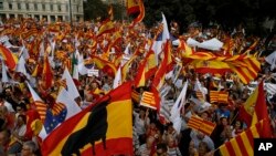 People wave flags of Catalonia and Spain as they celebrate a holiday known as "Dia de la Hispanidad" or Spain's National Day in Barcelona, Spain, Oct. 12, 2017.