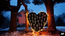 FILE - A memorial with crosses for the victims of the Sandy Hook massacre stands outside a home in Newtown, Conn., Dec. 14, 2013, the one-year anniversary of the shootings. A new documentary shows how a children's play helped the community heal.