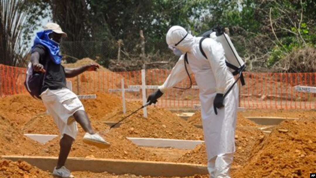 Seorang petugas kesehatan menyemprot seorang pria dengan disinfektan di untuk mencegah penularan Ebola di Monrovia, Liberia (11/3). (AP/Abbas Dulleh)