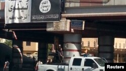 FILE - A fighter from the Islamic State, formerly known as the Islamic State of Iraq and the Levant (ISIL), mans an anti-aircraft gun mounted on the rear of a vehicle in Mosul, Iraq, July 16, 2014. 