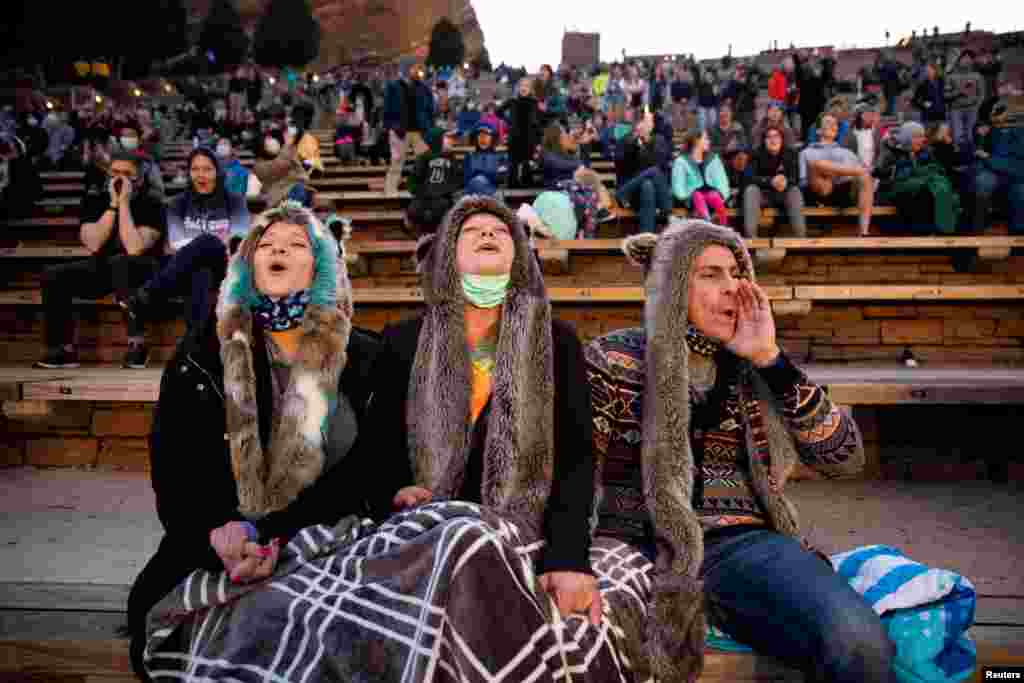 Anita Rose, Jim Galbreath and Dan Galbreath, participate in the &quot;8 o&#39;clock Howl&quot; that honors essential workers at the 80th anniversary season kickoff at Red Rocks Amphitheatre as the coronavirus disease (COVID-19) restrictions are eased in Morrison, Colorado, April 28, 2021.