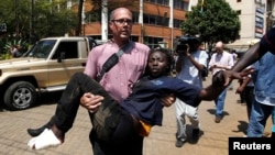 Seorang jurnalis menyelamatkan seorang perempuan yang terluka dalam baku tembak antara polisi dan kelompok bersenjata di pusat perbelanjaan Westgate di Nairobi, Kenya (21/9). (Reuters/Thomas Mukoya)