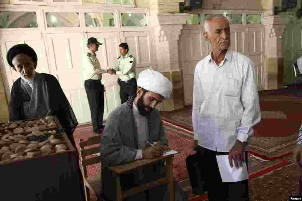 A cleric fills in his ballot paper during the Iranian presidential election at a mosque in Qom, June 14, 2013. 