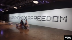 Two journalists relax in front of plaques memorializing journalists killed since 2016. The display was part of the Global Conference for Media Freedom.