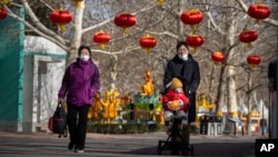 Seorang pria bersama anaknya di kereta dorong di sebuah taman di Beijing, 17 Januari 2023. (Foto: Mark Schiefelbein/AP Photo)