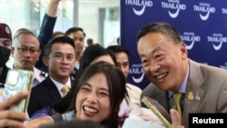 2023年9月25日，在泰国曼谷国际机场举行的首批为期五个月免签入境中国游客的欢迎仪式上，一名中国游客与泰国总理斯雷塔·塔维信合影。( 路透社)
