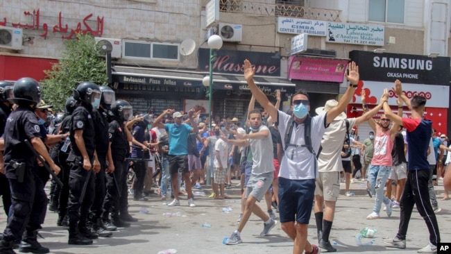 Para pengunjuk rasa berhadapan dengan polisi dalam unjuk rasa di Tunis, Tunisia, Minggu, 25 Juli 2021. 