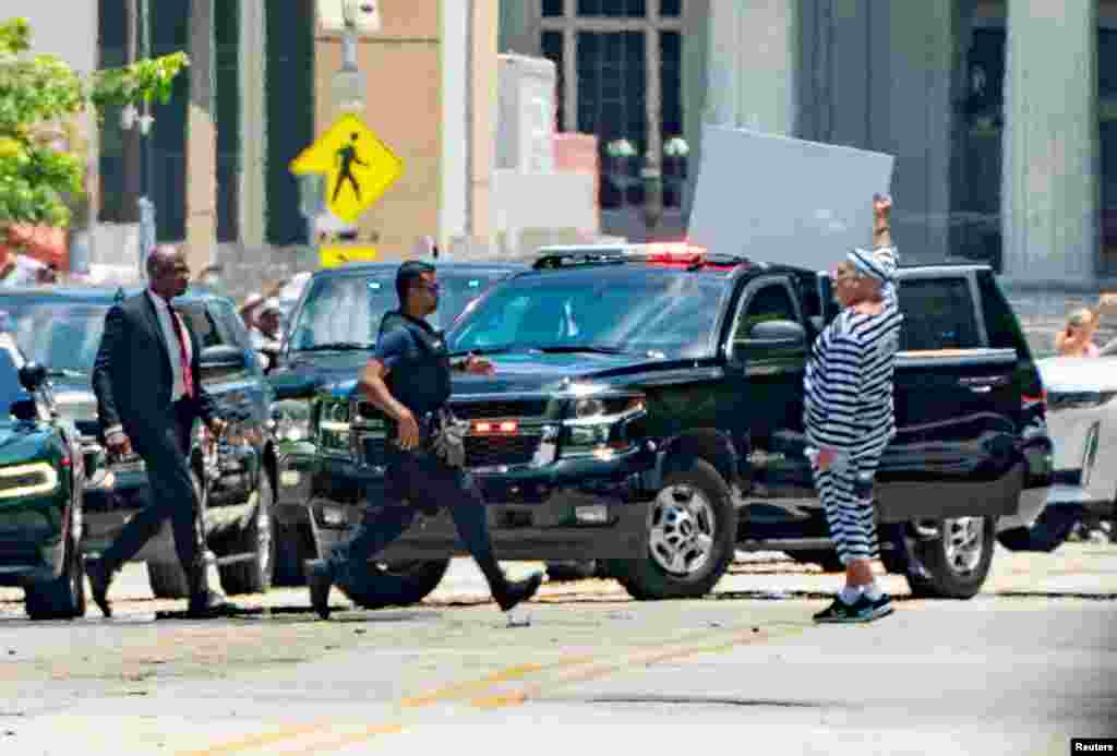 La policía y agentes de seguridad acordonaron previamente la zona por razones de seguridad.&nbsp;Un hombre hace un gesto cuando la caravana del expresidente de los Estados Unidos, Donald Trump, llega al Palacio de Justicia.