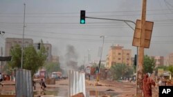 Smoke rises behind barricades laid by protesters to block a street in the Sudanese capital Khartoum to stop military vehicles from driving through the area on June 5, 2019.