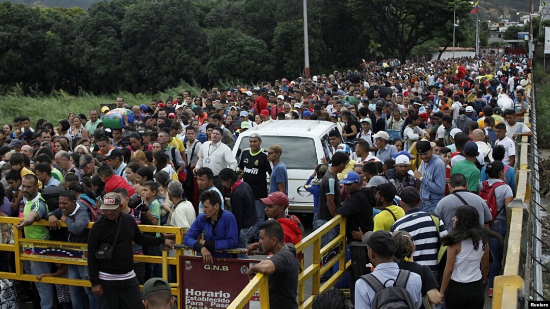 FILE - People queue to try to cross the Venezuela-Colombia border through Simon Bolivar international bridge in San Antonio del Tachira, Venezuela, Aug. 3, 2018.
