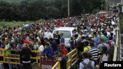 FILE - People queue to try to cross the Venezuela-Colombia border through Simon Bolivar international bridge in San Antonio del Tachira, Venezuela, Aug. 3, 2018.