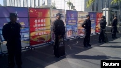 FILE - Policemen in riot gear guard a checkpoint near a courthouse where ethnic Uighur academic Ilham Tohti's trial is taking place in Urumqi, Xinjiang Uighur Autonomous Region, Sept. 17, 2014.