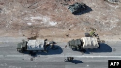 An aerial photo shows anti-government figthers riding a motorcycle past Syrian army military equipment and vehicles that were abandoned on the highway to Damascus, as they reach the town of Suran north of Syria's Hama city on Dec. 3, 2024.