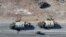 An aerial photo shows anti-government figthers riding a motorcycle past Syrian army military equipment and vehicles that were abandoned on the highway to Damascus, as they reach the town of Suran north of Syria's Hama city on Dec. 3, 2024.