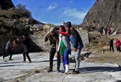 People help an injured woman to board a helicopter after a flash flood swept a mountain valley destroying dams and bridges, at Lata village in Chamoli district, in the northern state of Uttarakhand, India, Feb. 12, 2021.