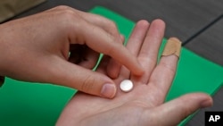 FILE - A patient prepares to take the first of two combination pills, mifepristone, for a medication abortion in Kansas City, Kansas, Oct. 12, 2022. On Nov. 19, 2024, a judge in Wyoming struck down an explicit prohibition on the use of medication to end pregnancy. 