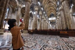 A tourist wearing a face mask takes pictures inside the Duomo gothic cathedral as it reopened to the public after being closed due to the COVID-19 virus outbreak in northern Italy, in Milan, March 2, 2020.