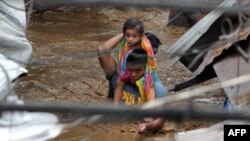 A policeman carries a young girl as he wades through a flooded street in Cagayan City on Dec. 22, 2017, after the Cagayan River swelled caused by heavy rains brought by Tropical Storm Tembin.