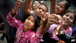 Niños migrantes, que forman parte de las caravanas de centroamericanos que buscan asilo en EE.UU., esperando caramelos que les ofreció un trabajador social en el refugio en Tijuana, el martes 20 de noviembre de 2018. 