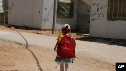 Seorang anak perempuan berjalan ke sekolah di Kamp Pengungsi Zaatari untuk pengunsi Suriah di Yordania bagian utara (foto: AP Photo/Reem Saad)