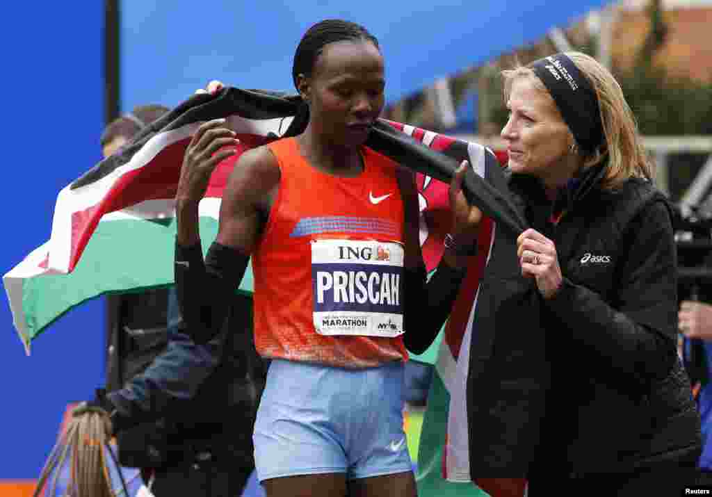 Priscah Jeptoo (kiri) dari Kenya diselimuti bendera negaranya oleh Mary Wittenberg, presiden asosiasi pelari New York Road Runners, setelah Jeptoo memenangkan maraton. (Reuters/Mike Segar)