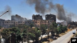 In this Sunday, July 7, 2013, citizen journalism image, which has been authenticated based on its contents and other AP reporting, black smoke rises from buildings damaged by Syrian government airstrikes and shelling in Homs.