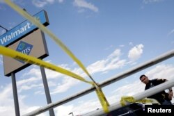 FILE - A police officer stands next to a police cordon after a mass shooting at a Walmart in El Paso,Texas, Aug. 3, 2019.