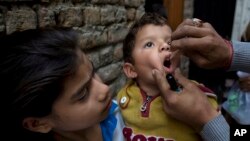 FILE - A Pakistani health worker gives a polio vaccine to a child in Islamabad, Dec. 8, 2014.