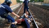Hungarian policemen stand by the family of migrants as they wanted to run away at the railway station in the town of Bicske, Sept. 3, 2015.