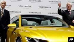 Then-Volkswagen CEO Martin Winterkorn, right, and then-Porsche CEO and member of the board of Volkswagen, Matthias Mueller, left, pose for the media beside a car prior to the company's annual press conference in Berlin, Germany, March 12, 2015.