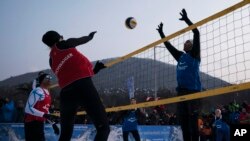 FILE - Brazil's Giba, right, tries to block Austria's Stefanie Schwaiger during a snow volleyball exhibition match at the Austria House in Pyeongchang, South Korea, Feb. 14, 2018. 