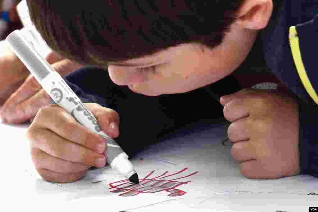 Một em bé chăm chú trang trí cho chiếc diều của mình.