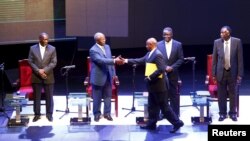 Uganda President Yoweri Museveni (with file) shakes hands with Amama Mbabazi, former prime minister, during a presidential debate in Kampala, Feb. 13, 2016.