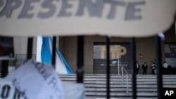 Personal de seguridad custodia una puerta mientras manifestantes protestan frente a la Fiscalía General de la República en la Ciudad de Guatemala, el miércoles 18 de octubre de 2023.