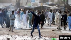 Seorang pendukung partai politik Islam Tehreek-e-Labaik Pakistan (TLP) melemparkan batu ke arah polisi selama protes terhadap penangkapan pemimpin mereka di Lahore, Pakistan 13 April 2021. (Foto: Reuters)