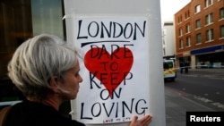 Une femme pose une affiche sur le London Bridge, après l'attaque à Londres, le 4 juin 2017. 