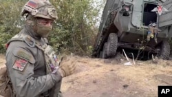 FILE - In this photo taken from video released by the Russian Defense Ministry on Sept. 13, 2024, a Russian soldier stands next to a damaged Ukrainian military vehicle in the Russian-Ukrainian border area in the Kursk region, Russia.