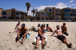 A group of men in town for a bachelor's party sit on the beach in San Diego, April 27, 2021. Many in the group had already been vaccinated.