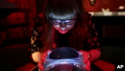 A member of British Library staff poses with a crystal ball for a picture at the "Harry Potter - A History of Magic" exhibition at the British Library in London, Oct. 2017. (AP Photo)