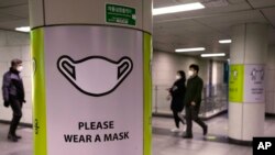 People wearing face masks pass by posters reminding precautions against the coronavirus at a subway station in Seoul, South Korea, Nov. 17, 2021. 