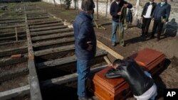 Peruvian migrant Jose Collantes weeps on the coffin that contains the remains of his wife, Silvia Cano, who died due to COVID-19 complications, according to Collantes, at a Catholic cemetery in Santiago, Chile, July 3, 2020. 