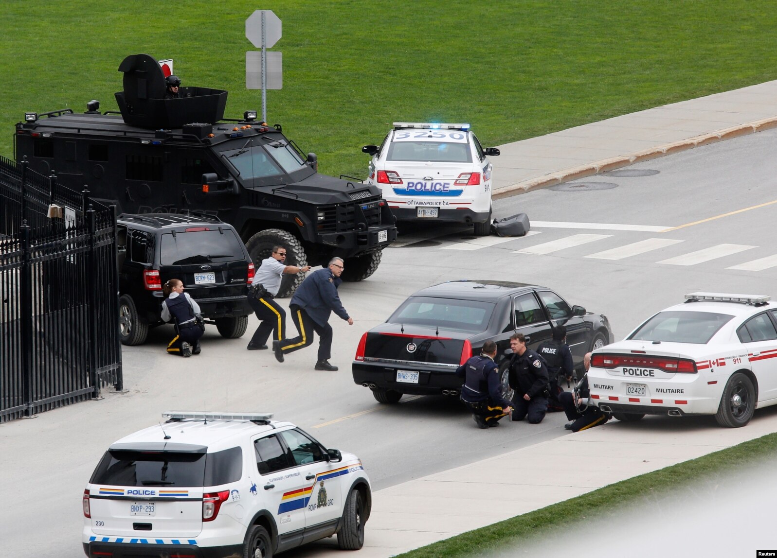 Police officers take cover near Parliament Hilll following a shooting incident in Ottawa, Canada. A Canadian soldier was shot and killed at the National War Memorial in downtown Ottawa and a gunman was shot and killed in a nearby parliament building, media and witnesses reported.