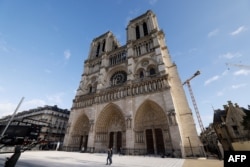 La gente camina frente a la catedral de Notre-Dame de París, antes de su ceremonia de reapertura oficial después de más de cinco años de trabajos de reconstrucción tras el incendio de abril de 2019, en París el 7 de diciembre de 2024.