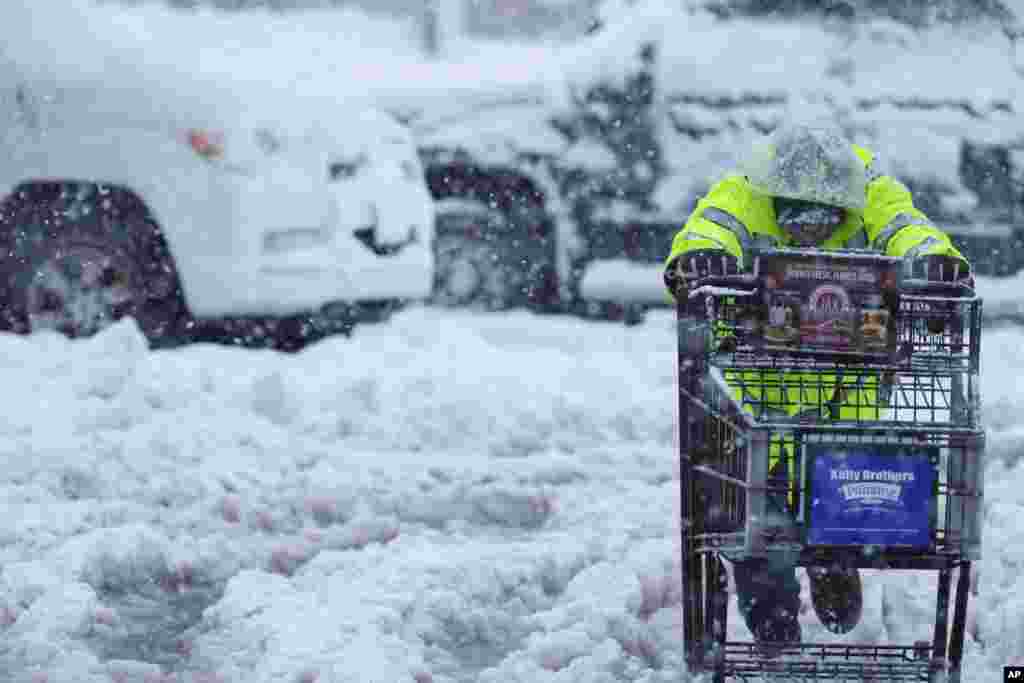 A person pushes a shopping cart on a snow-covered parking lot during a storm in Truckee, California, Feb. 13, 2025.