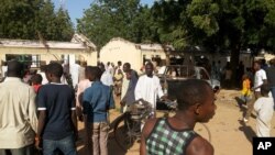 Une foule contemple le lieu d'un attentat à la bombe à l'école technique et scientifique publique de Potiskum, Nigeria, le 10 novembre 2014. 