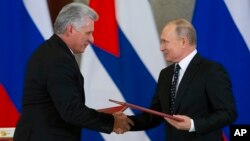 Russian President Vladimir Putin, right, and Cuban President Miguel Diaz-Canel, exchange documents after their talks in the Kremlin, in Moscow, Russia, Nov. 2, 2018.