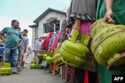 Warga mengantre membawa tabung gas untuk membeli Liquefied Petroleum Gas (LPG) bersubsidi untuk memasak di sebuah pusat distribusi di Lambaro, provinsi Aceh, Indonesia, pada 2 Mei 2023. (CHAIDEER MAHYUDDIN / AFP)