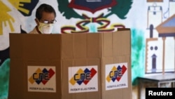 ARCHIVO - Un hombre parado frente a una cabina de votación en un colegio electoral durante las elecciones parlamentarias en Caracas, Venezuela, en diciembre de 2020.